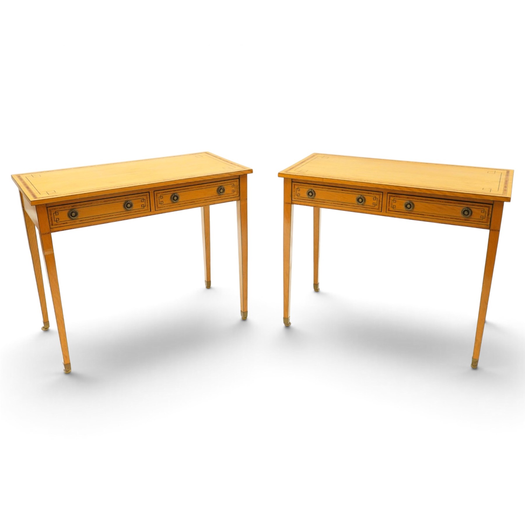 Pair of George III design inlaid satinwood console or side tables, rectangular top with mahogany cross-banding and ebony stringing, fitted with two drawers with brass ring handles, on square tapering supports with brass cups and castors