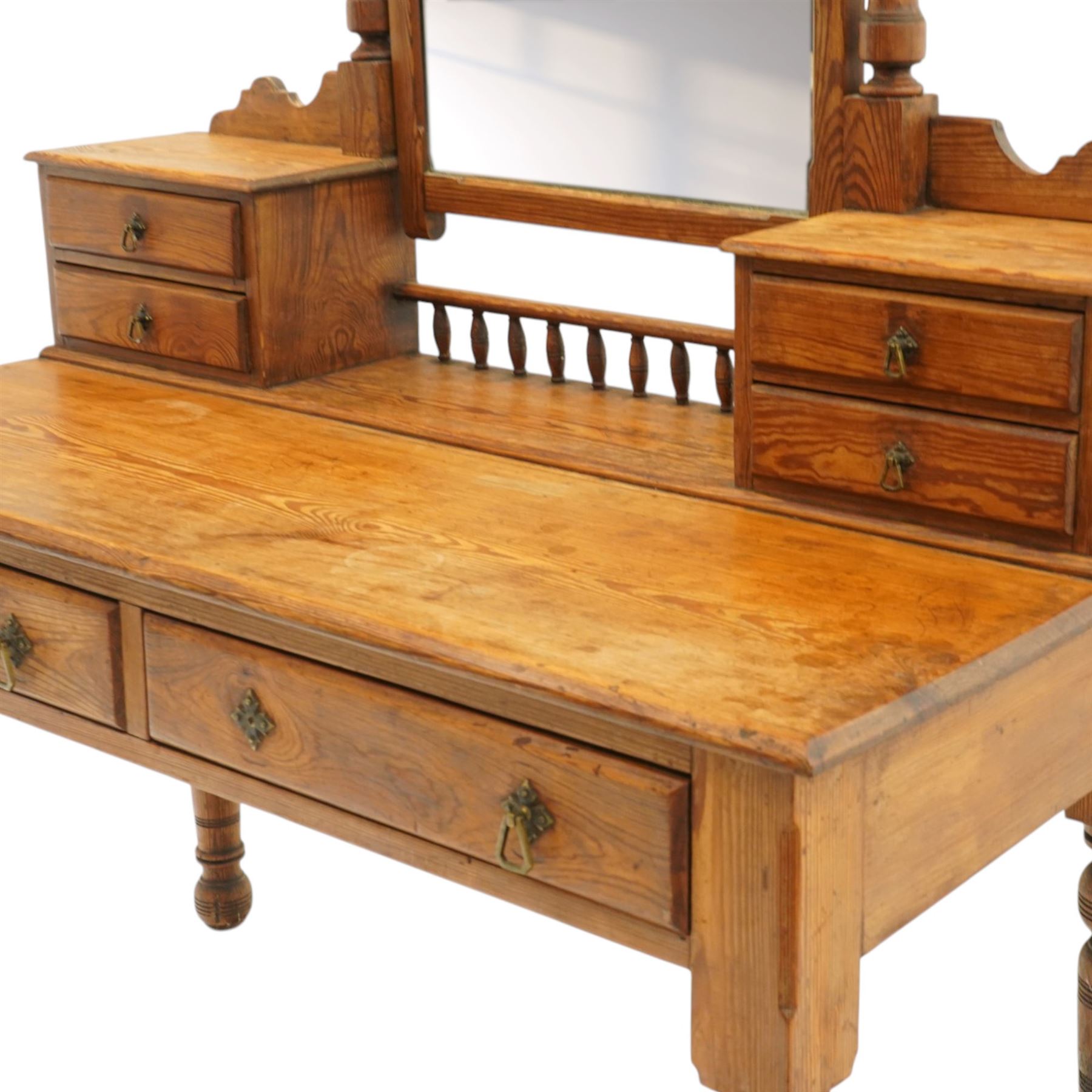 Victorian stripped pine dressing table, rectangular top over two drawers with brass handles, the raised back fitted with adjustable rectangular mirror, spindle gallery flanked by two short jewellery drawers either side, on turned legs