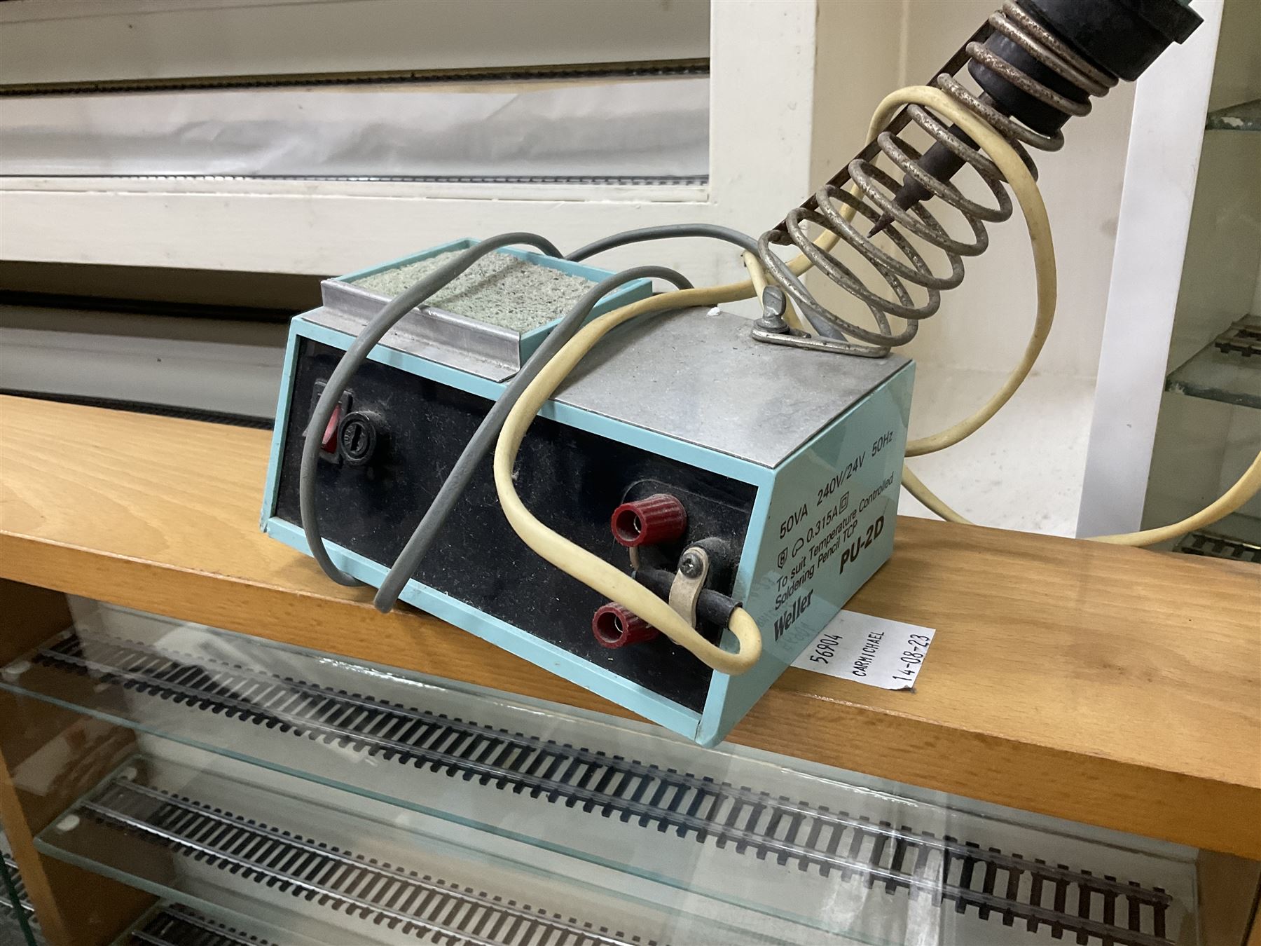 Six shelved cabinets for displaying ‘00’ gauge locomotives comprising plain plywood and white painted examples with track applied to various shelves, largest H63cm, W107cm, D27cm; Collection of tools for building model locomotives to include Weller PU-2D Soldering Pencil and Standard Tip Soldering Iron 20W/230V, Humbrol Modellers Airbrush, Power Supply Units and two wooden chests one of which housing a collection of tools including tweezers, scalping tools, wrenches etc 
