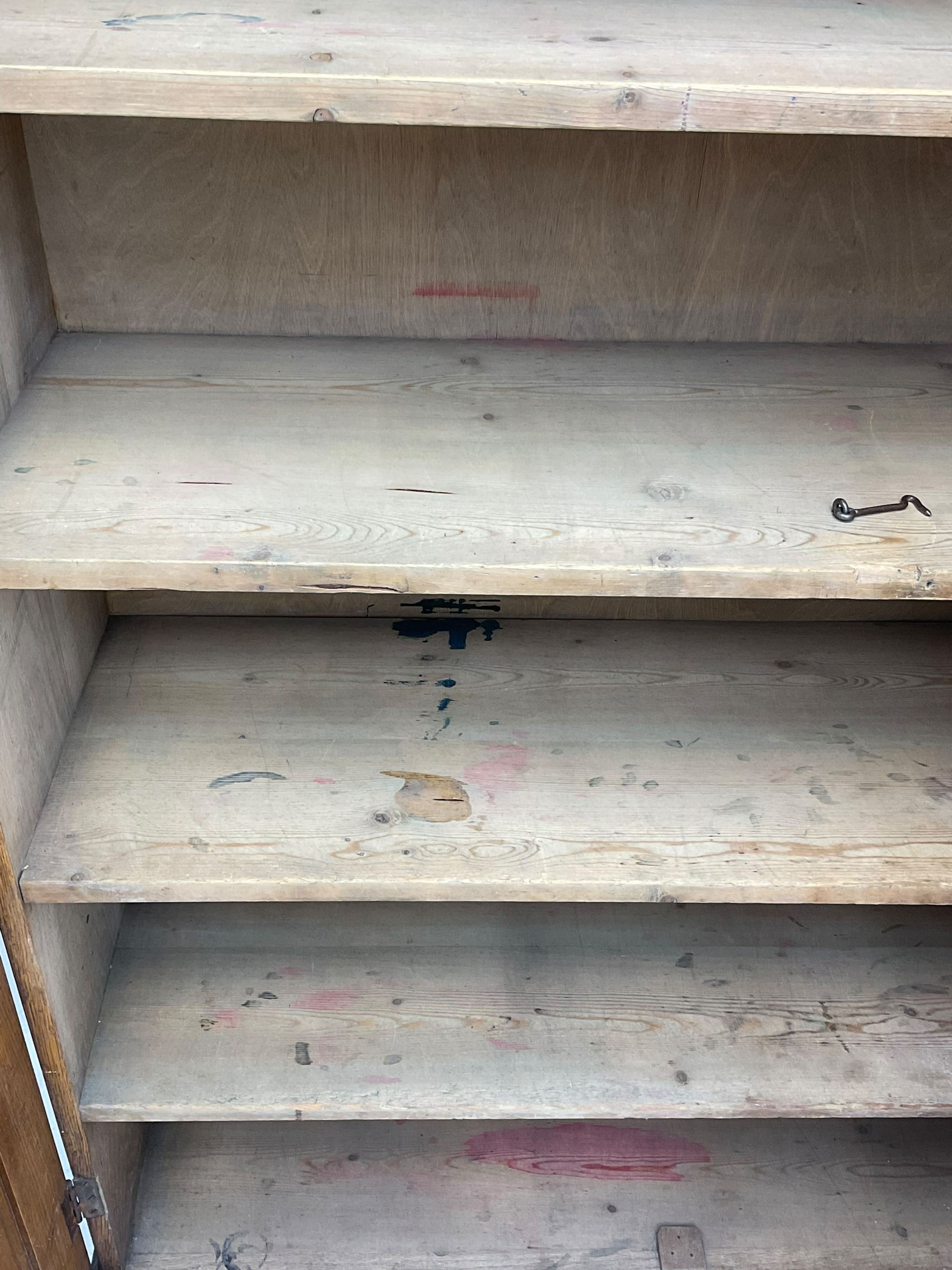 The North of England School Furnishing Company Limited Darlington - early 20th century oak school cupboard, projecting moulded cornice over two panelled doors, fitted with shelves, on chamfered plinth base 