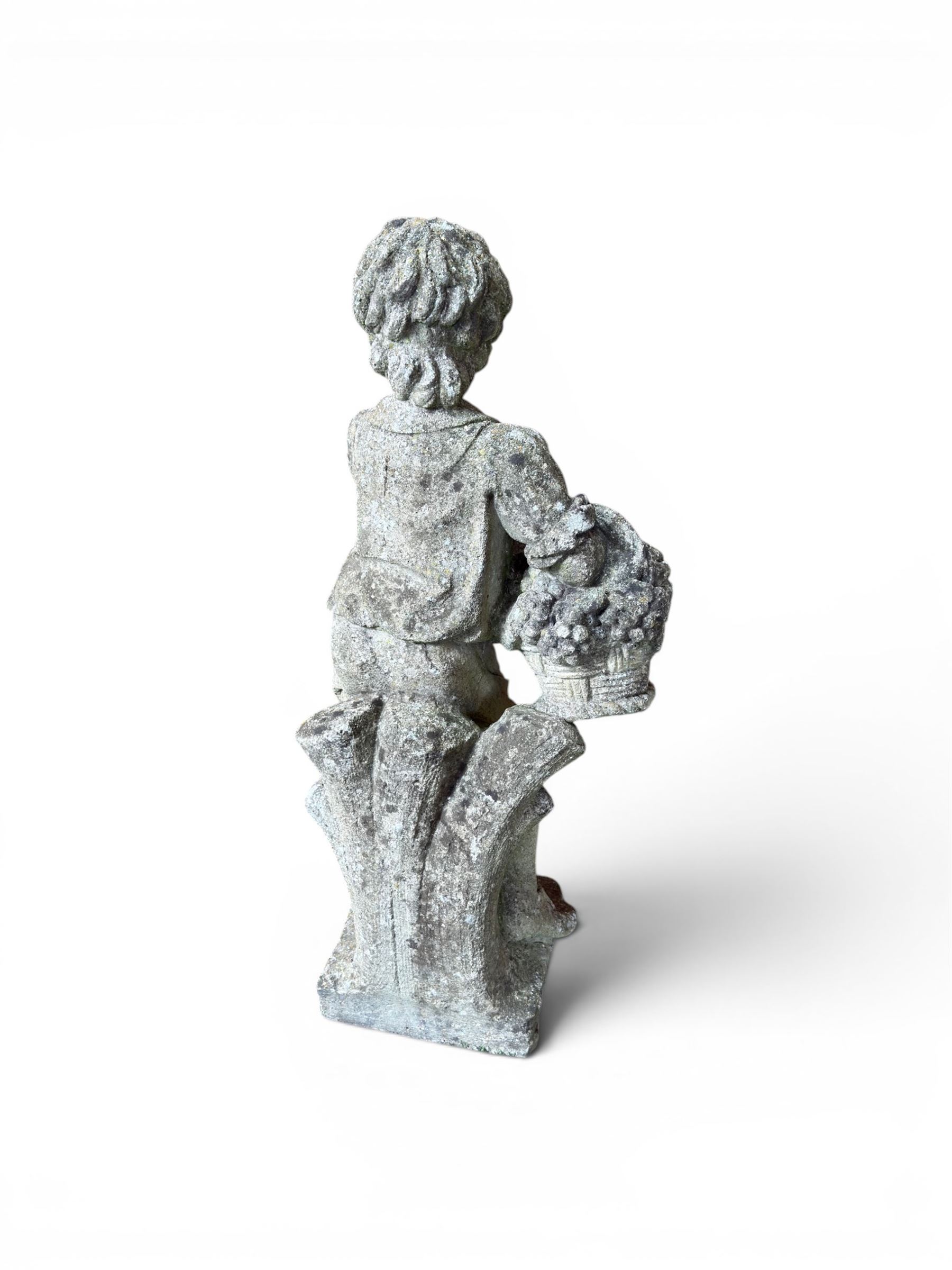 Weathered cast stone garden figure depicting a child holding a fruit basket