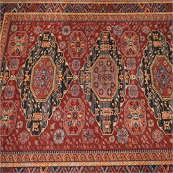 Persian Karabagh design rug, red madder field with three linked octagonal medallions surrounded by floral geometric motifs within multiple stylized borders 