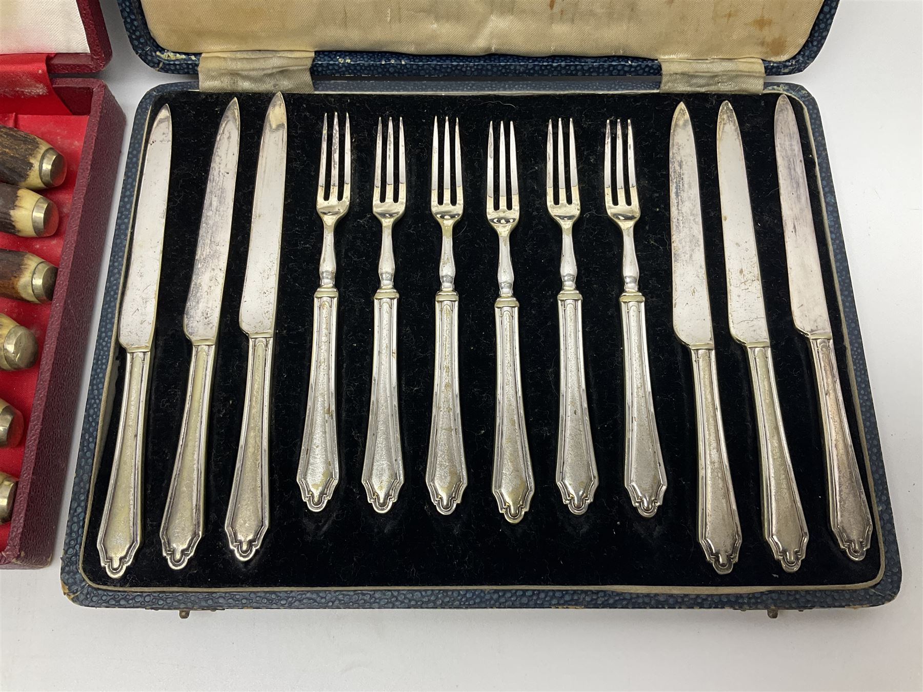 Set of six stag horn handled knives by Cooper Brothers and Sons, together with a set of silver plated dessert knives and forks for six place settings, both within fitted cases