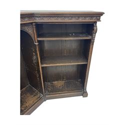Victorian carved oak corner bookcase, L-shaped form, moulded top over lunette carved frieze, decorated with S-scroll and mask carved corbels with trailing acanthus leaves, fitted with adjustable shelves, on moulded plinth base 