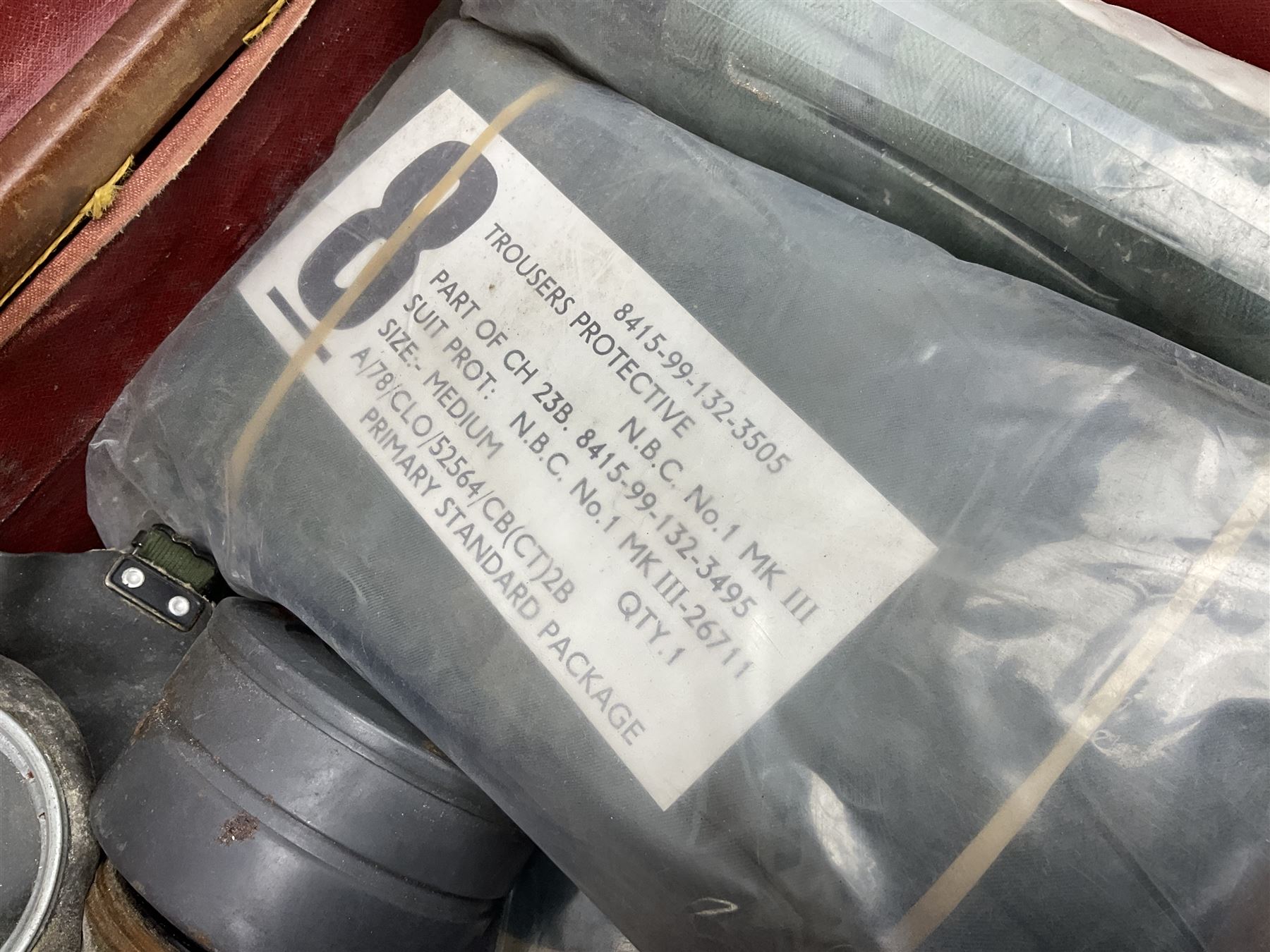 Early 20th century leather suitcase marked to the top 'Major P.M. Newton R.E. Crossways, Bridlington, East Yorkshire' 60 x 40cm; another similar leather suitcase marked W.D. to the lid; three post-WW2 respirators; and three unopened pairs of British Army N.B.C. (Nuclear Biological Chemical) No.1 Mk.III Trousers Protective (8)