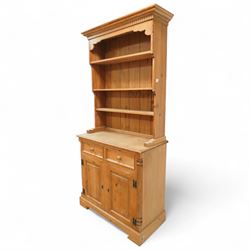 20th century stripped pine dresser, the open rack with dentil frieze and fixed shelves over a cupboard base with two drawers and fielded panel doors, flanked by stop-fluted uprights, on a moulded plinth
