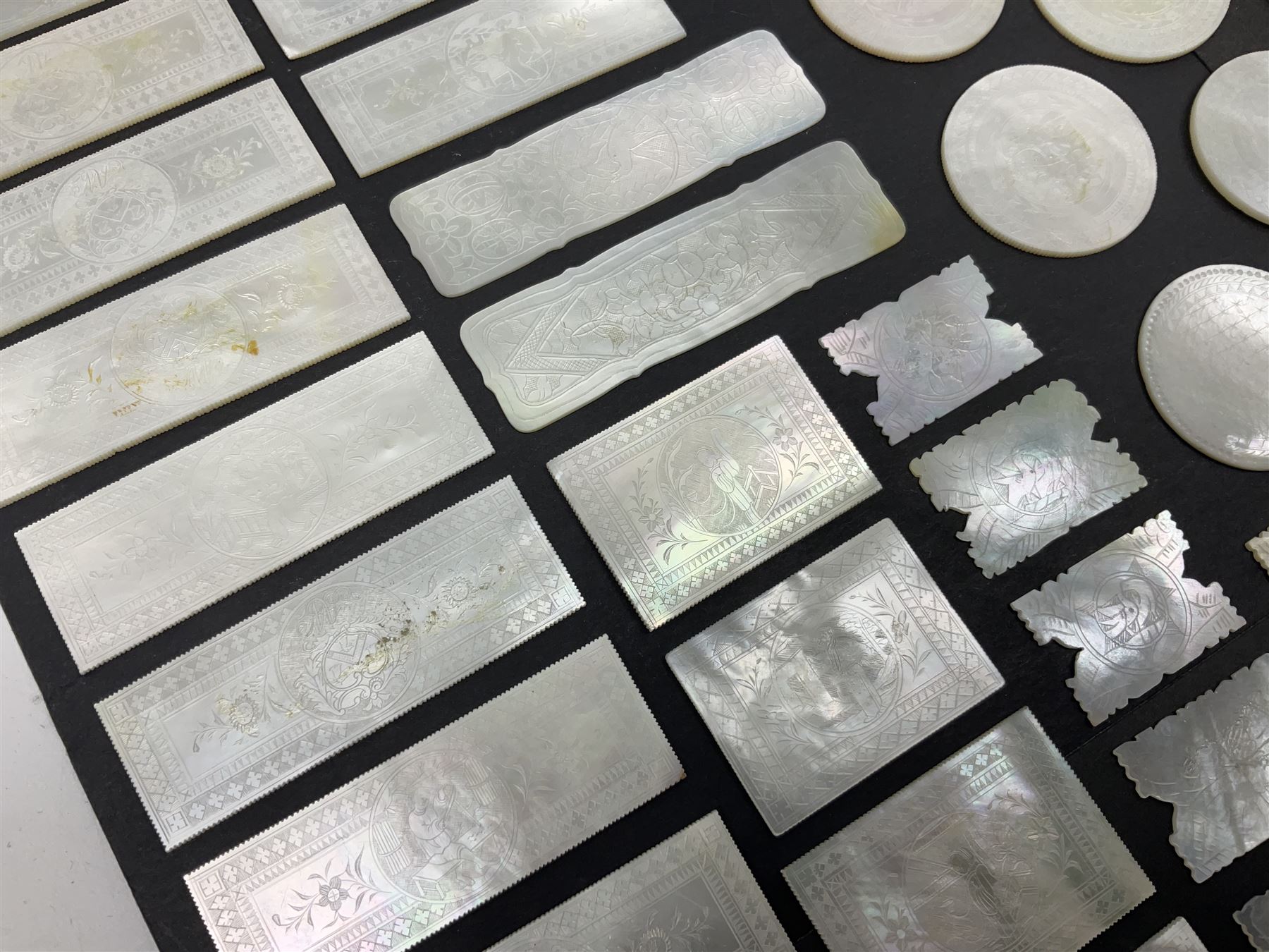 Collection of fifty seven Chinese mother of pearl gaming counters or tokens, of various size and form including rectangular, circular and fish shaped examples, various decoration including floral motifs, largest rectangular examples L6cm