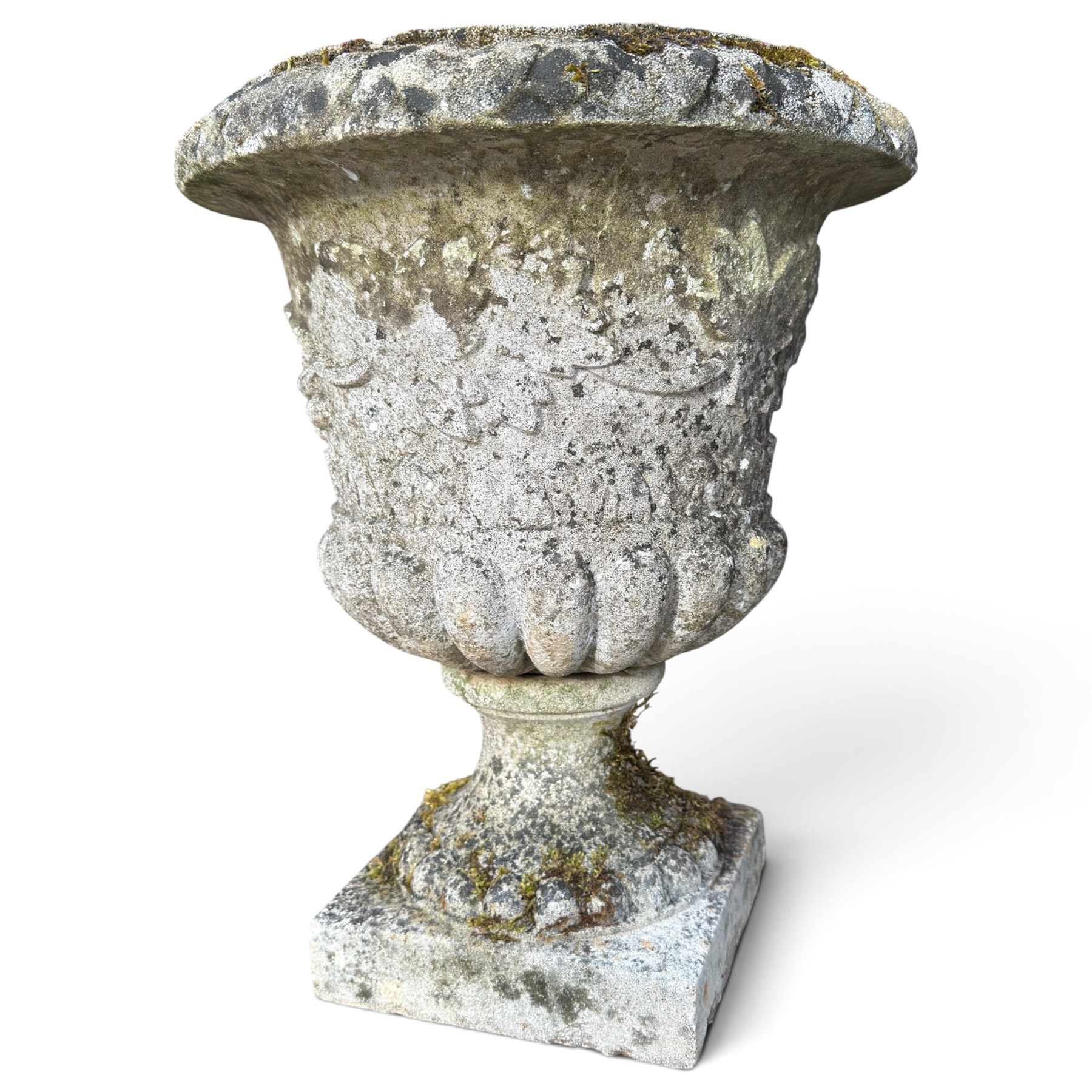 Set of four weathered composite stone urns of campana form, the everted leaf-moulded rolled rim over a body decorated with scrolling fruiting grapevines in relief, over a gadrooned underbelly and waisted socle, lobed collar on square base