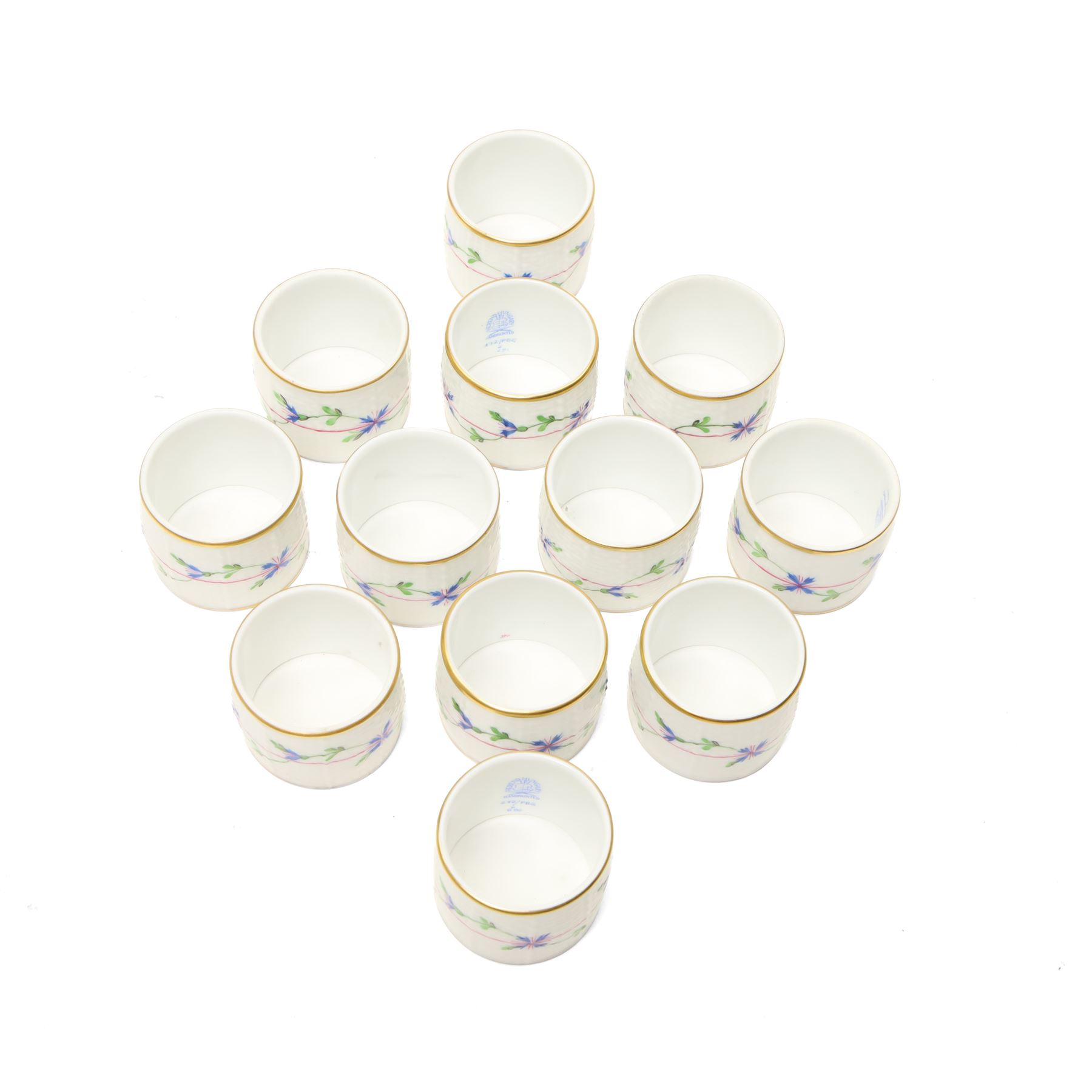 Set of twelve Herend porcelain napkin rings painted with trailing flowers and leaves on a moulded ground