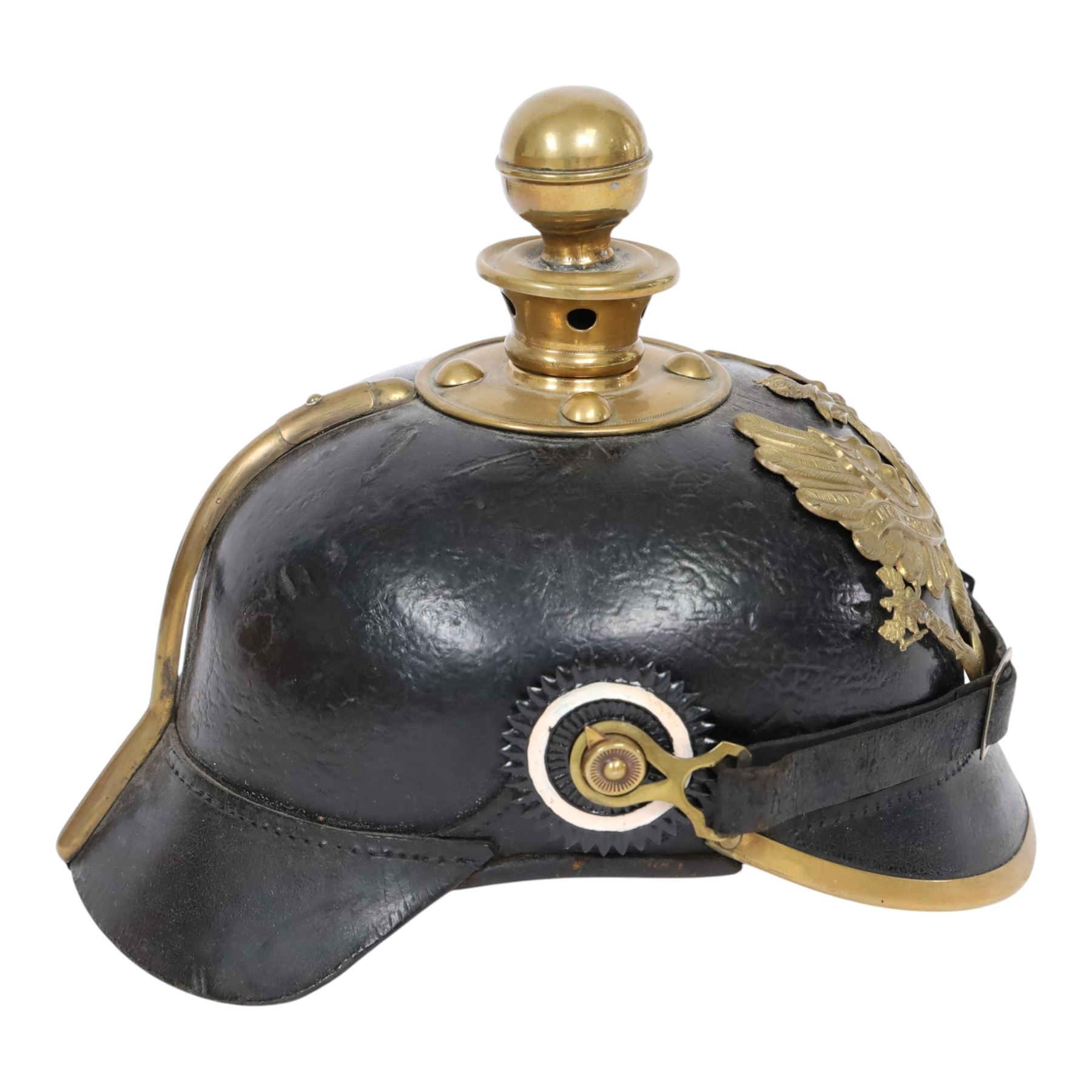 WWI Prussian EM M1895 artillery Pickelhaube, circa 1895, the black leather skull with brass ball finial, brass eagle helmet plate and leather chin strap, one side with a black cockade, the other black and red