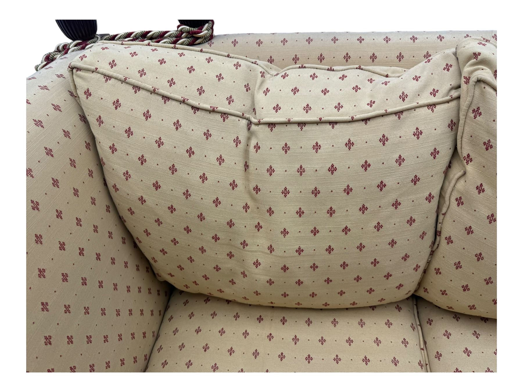 20th century Knole design two seat sofa, high back and double drop-arm joined by mahogany finials and ties, upholstered in camel ground fabric with red lozenge design, on turned supports with brass castors