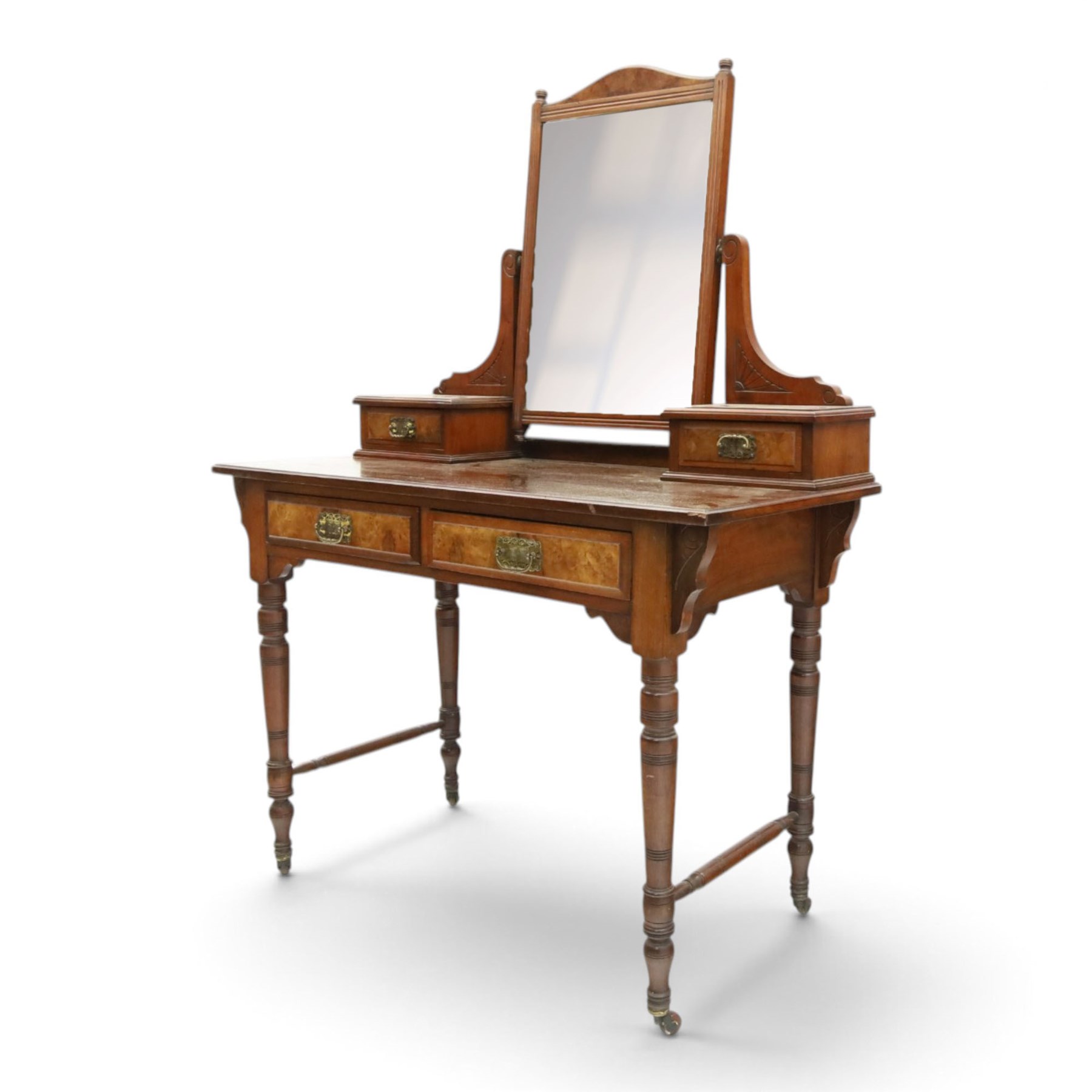 Late Victorian figured walnut and mahogany dressing table, raised swing-mirror back over trinket drawers, fitted with two drawers with brass Aesthetic Movement handles, on ring-turned supports with ceramic castors