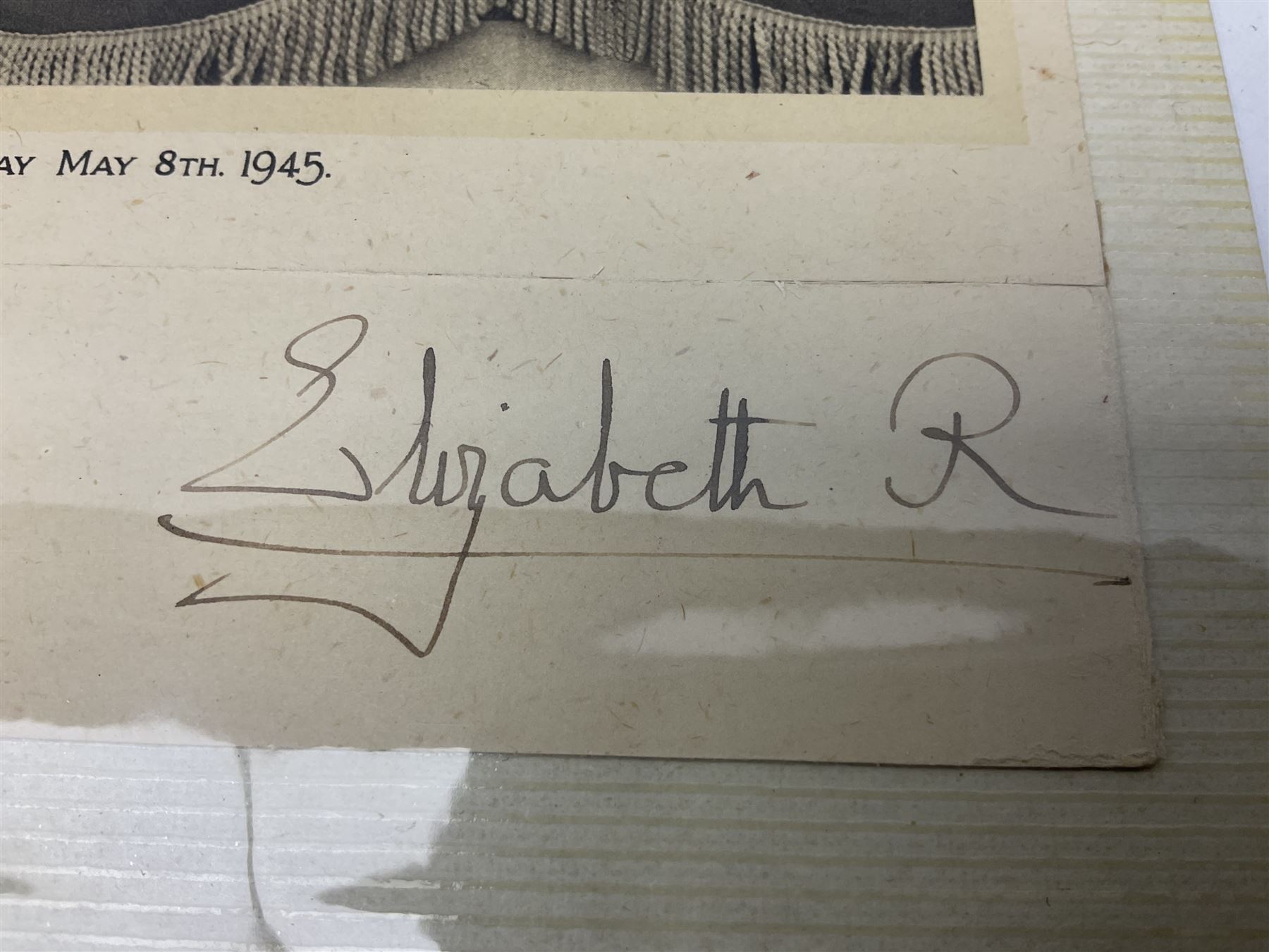 King George VI and Queen Elizabeth - the photograph and signatures only from a 1945 Christmas card depicting The Royal Family waving from the balcony of Buckingham Palace, on V-E Day Tuesday May 8th 1945, signed 'George R.I. Elizabeth R.'