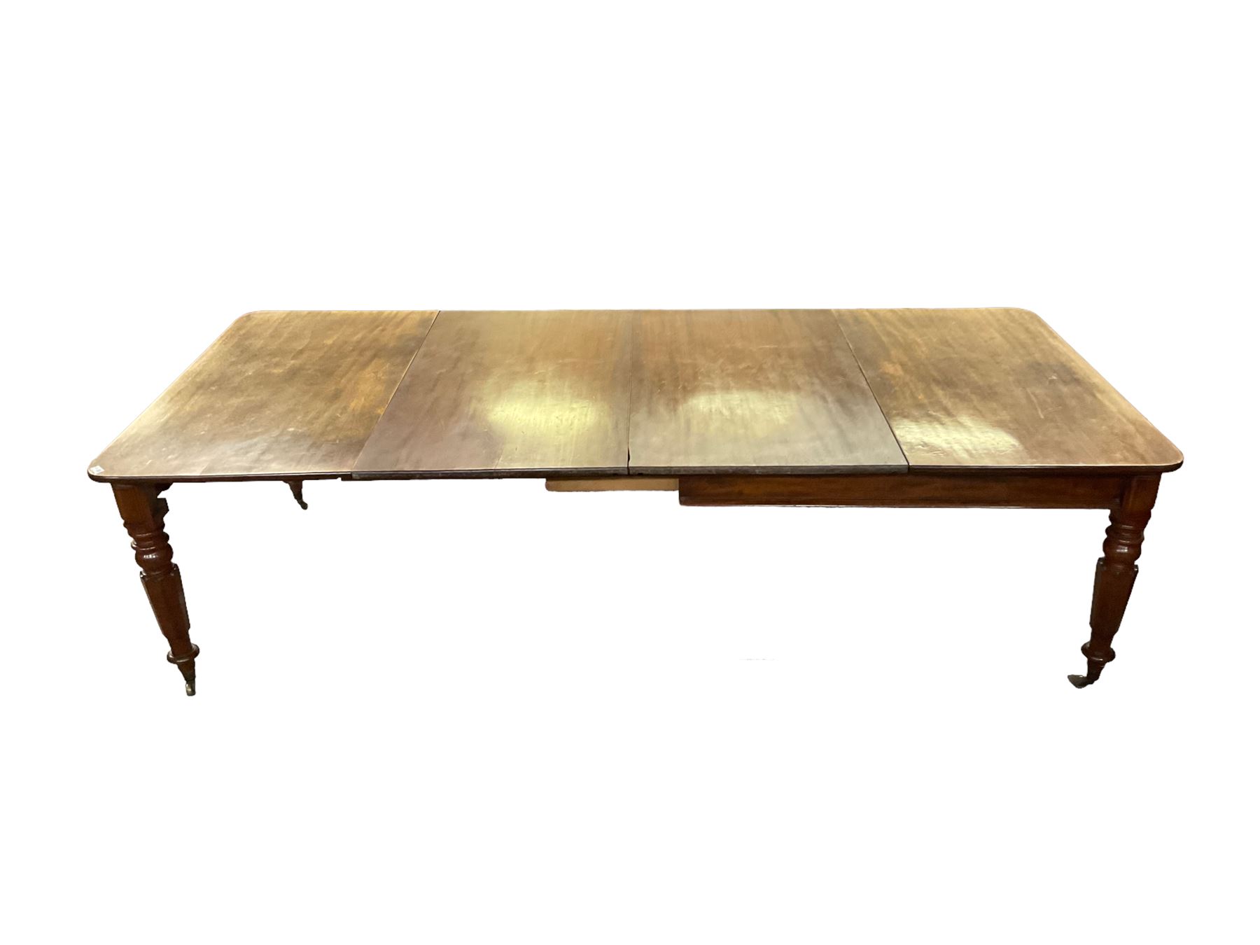 Late 19th century extending mahogany dining table, square top with banded frieze rail, raised on turned octagonal supports with  brass cups and castors, with two additional leaves