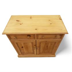 Contemporary pine storage cabinet, the rectangular top with rounded corners, over twin drawers and panelled cupboard doors, fitted with turned knob handles, plinth base
