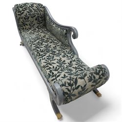 Regency design hardwood-framed chaise longue, scrolled back upholstered in leafy branch pattern fabric, reeded and scroll carved frame, on out splayed feet with brass paw castors
