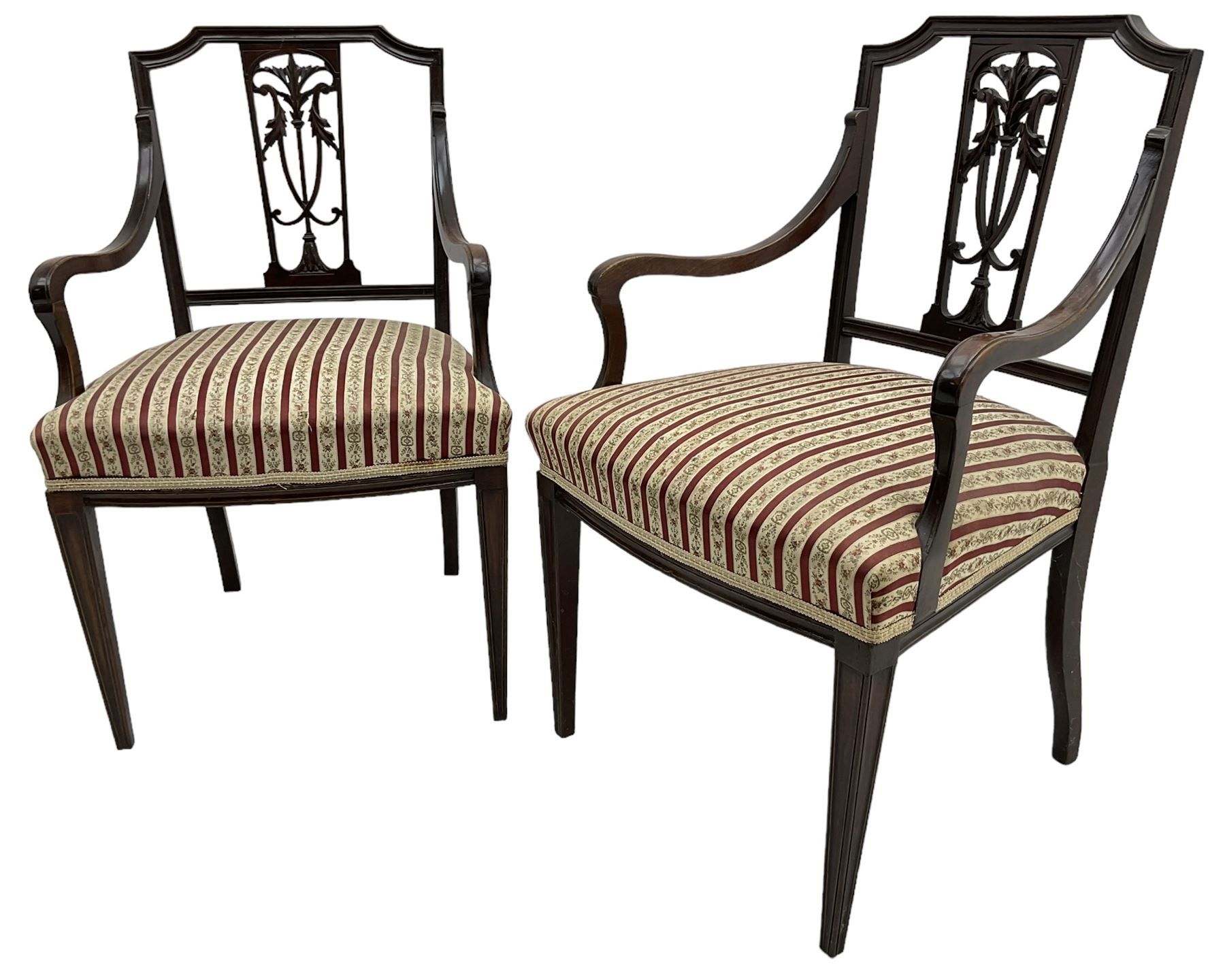 Edwardian mahogany framed three-piece salon suite - two-seat sofa, stepped cresting rail over acanthus and scroll carved pierced splat, upholstered in striped fabric (W124cm, H87cm, D62cm); and a pair of matching armchairs (W60cm) 