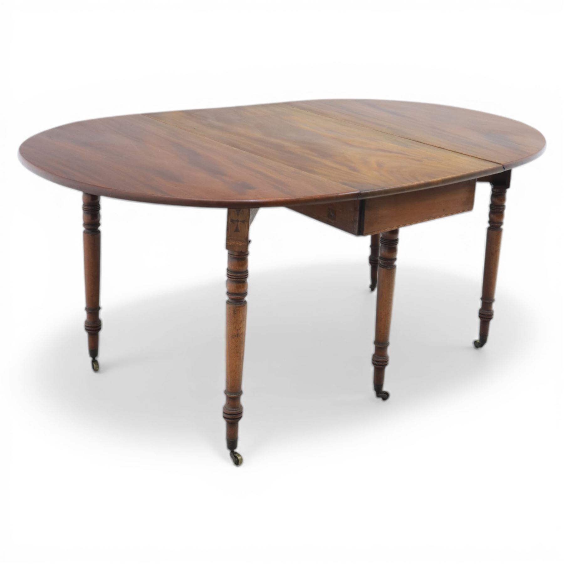 Early 20th century mahogany inlaid oval drop leaf dining table, the crossbanded and line inlaid top with twin hinged leaves (extends to 165cm), plain frieze centred by inlaid panel with stylised star motif, raised on four ring turned tapering supports terminating in brass caps and castors