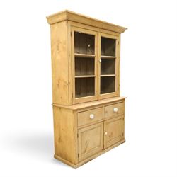 Victorian stripped pine and glazed dresser, projecting ovolo cornice over glazed doors enclosing two shelves, the base fitted with two drawers over panelled cupboards with ceramic handles, on moulded skirted base
