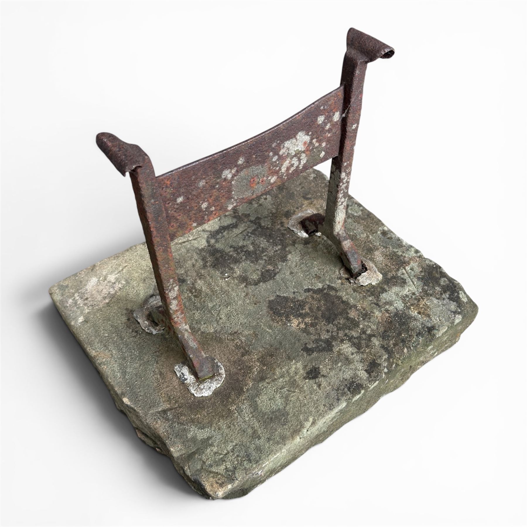 19th century cast iron boot scraper, mounted on a rectangular hewn stone slab base, with scrolled twin upright supports and scraper bar, in weathered finish