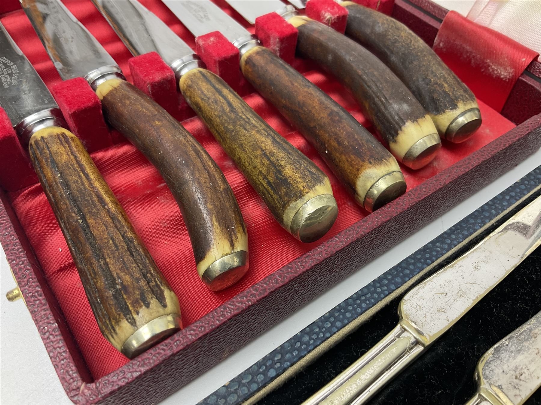 Set of six stag horn handled knives by Cooper Brothers and Sons, together with a set of silver plated dessert knives and forks for six place settings, both within fitted cases