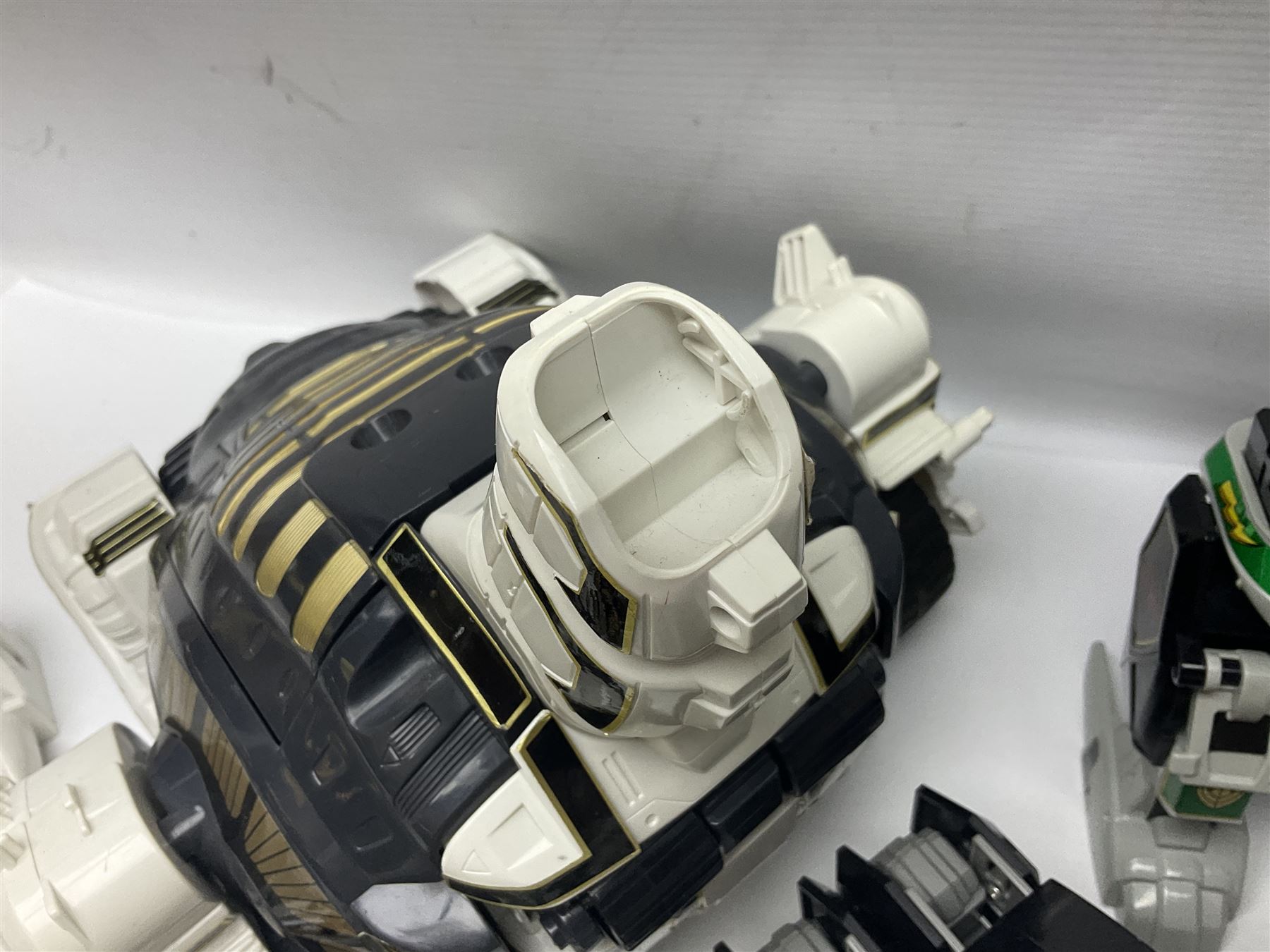 Collection of early 90s Mighty Morphin’ Power Rangers Zords, figures and accessories. Titanus the Carrier Zord, marked Bandai 1991; Green Dragonzord, incomplete; 1994 White Tigerzord with original instruction manual; 1993 Triceratops Dinozord, Mastodon Dinozord and Sabertooth Tiger Dinozord, Pterodactyl Dinozord, missing guns; with 1993 Power Morpher and original Power Coins, with further related figures, accessories and weapons