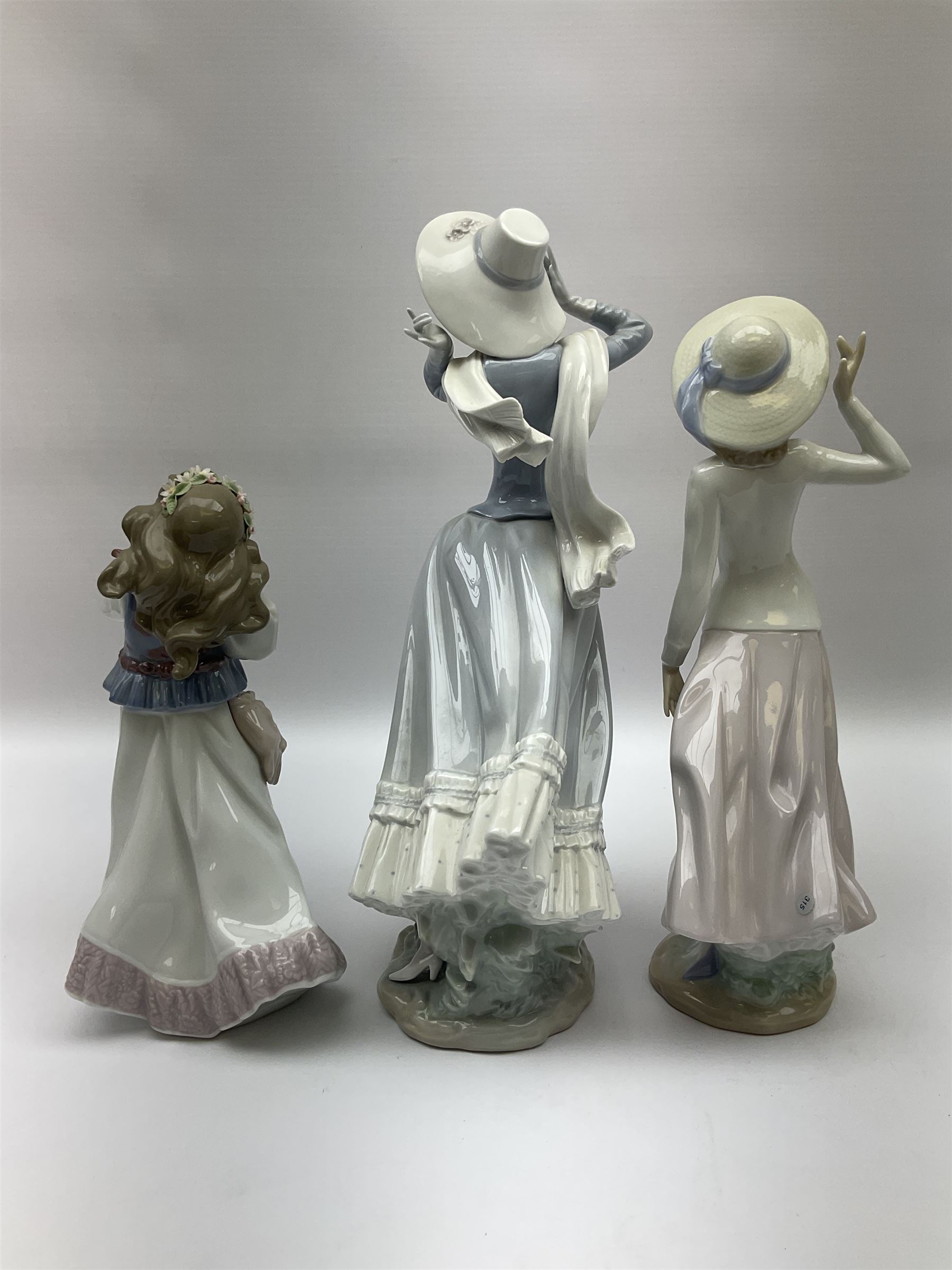 Three Lladro figures, comprising, Dreams of Summer Past no 6401, Spring Breeze no 4936 and Breezy Afternoon 5682 together with Lladro plaque Art Brings us Together no 7677, all in original boxes, largest example H35cm