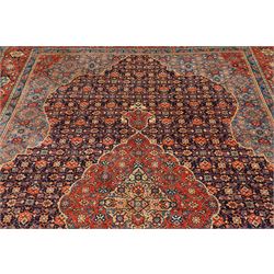Persian indigo ground Herati rug, the busy field with a central lozenge pole medallion surrounded by repeating Herati motifs, within a shaped spandrel border the crimson guard band decorated with repeating palmette motifs