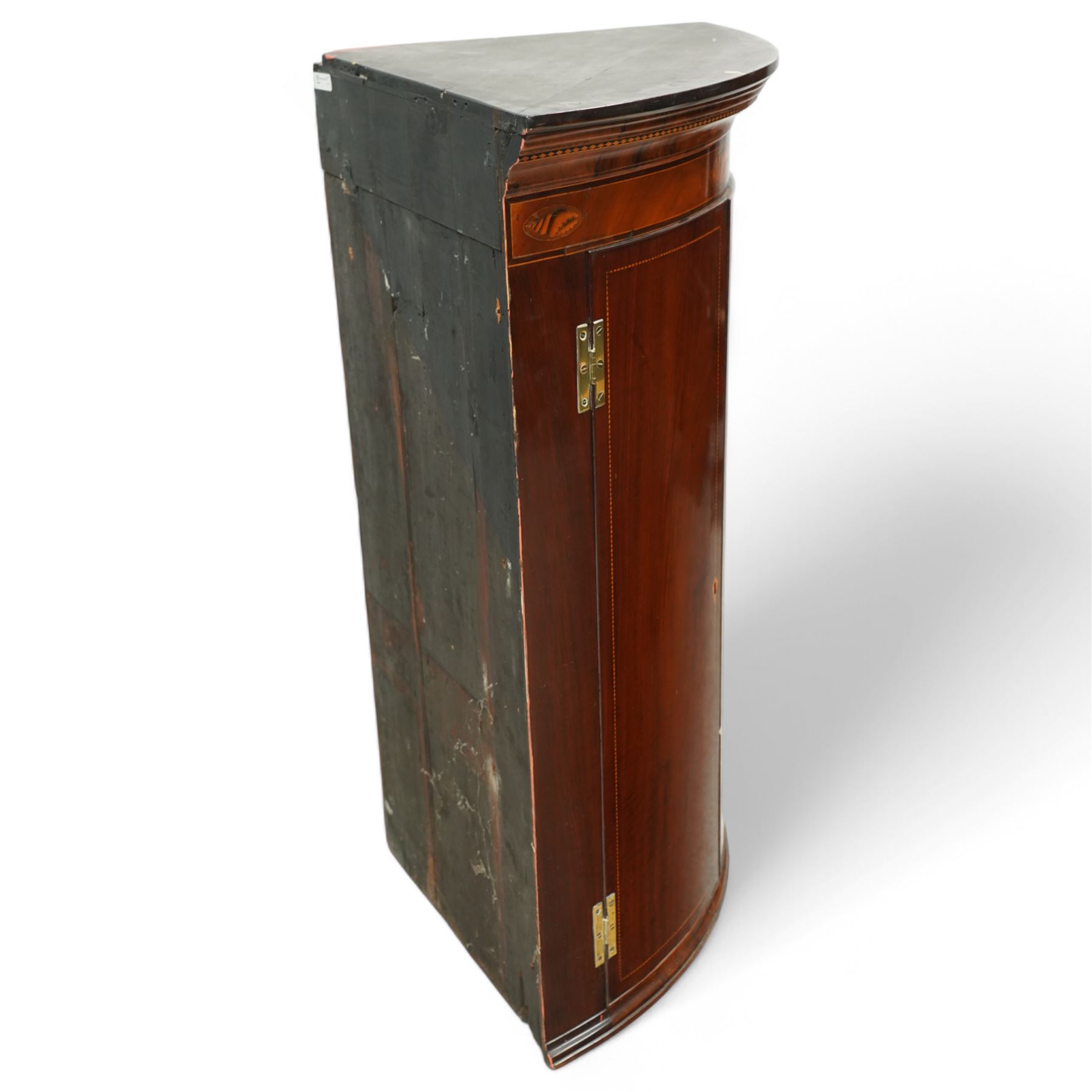George III inlaid mahogany cylinder corner cupboard, projecting moulded cornice over figured frieze inlaid with shell motifs, two doors with checkered stringing enclosing three shelves, circa 1800