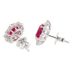 Pair of 18ct white gold ruby and diamond earrings, each stud set with a single oval cut ruby, surrounded by twelve round brilliant cut diamonds, stamped, total ruby weight approx 3.10 carat, total diamond weight approx 0.50 carat