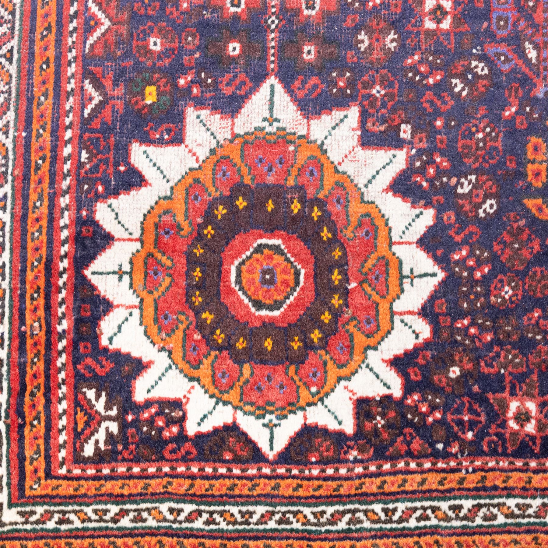 Qashqai wool carpet, red diamond-shaped field decorated with three stepped pole medallions, floral rosettes and scattered stylised motifs, within dark blue spandrels and multiple geometric guard borders