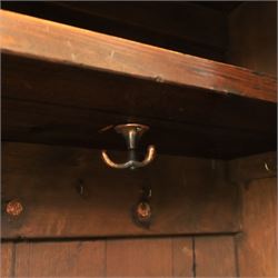 20th century dark stained oak hall robe, cantered sides enclosing a hooks and a shelf, panelled and carved sides, raised on stile supports
