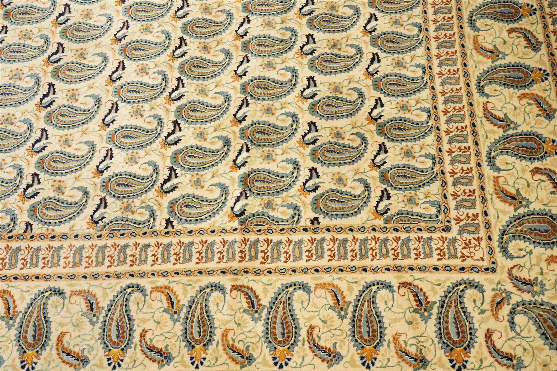Central Persian Kashan hand-knotted carpet, ivory field densely decorated with all-over repeating botehs motifs, arranged in rows and enclosed by scrolling vine work and floral sprays, in a palette of indigo, pale blue, sage green and muted terracotta tones, within ivory borders of small boteh motifs flanked by border within large scale boteh motifs with multiple guard stripes, with cotton fringe ends 