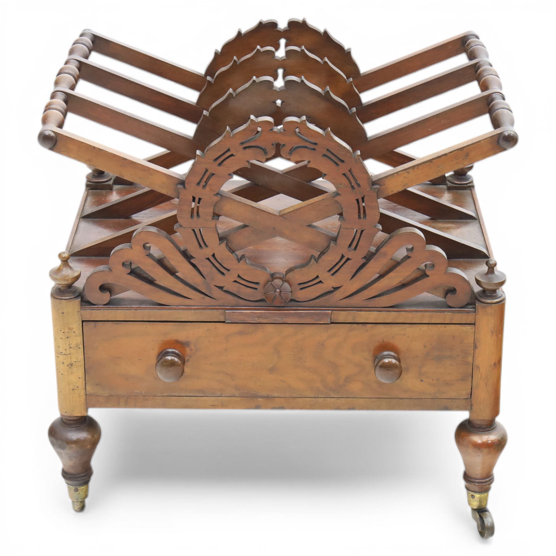 19th century mahogany music canterbury, with pierced dividers united by turned handles, above a single frieze drawer, raised upon baluster supports on brass castors