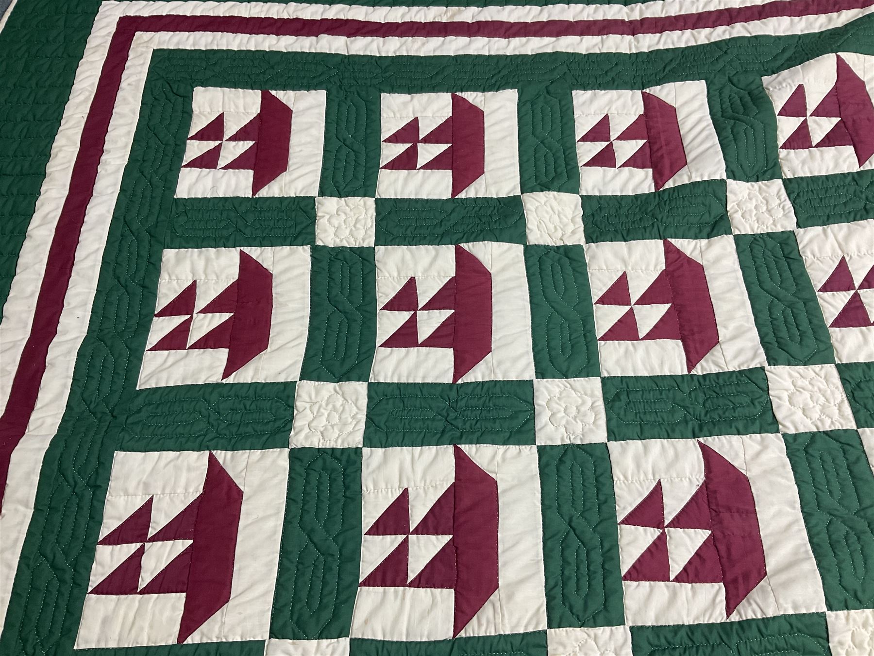 20th century quilt, with repetitive ship design to the centre within a cream red and green boarder, 227cm x 222cm