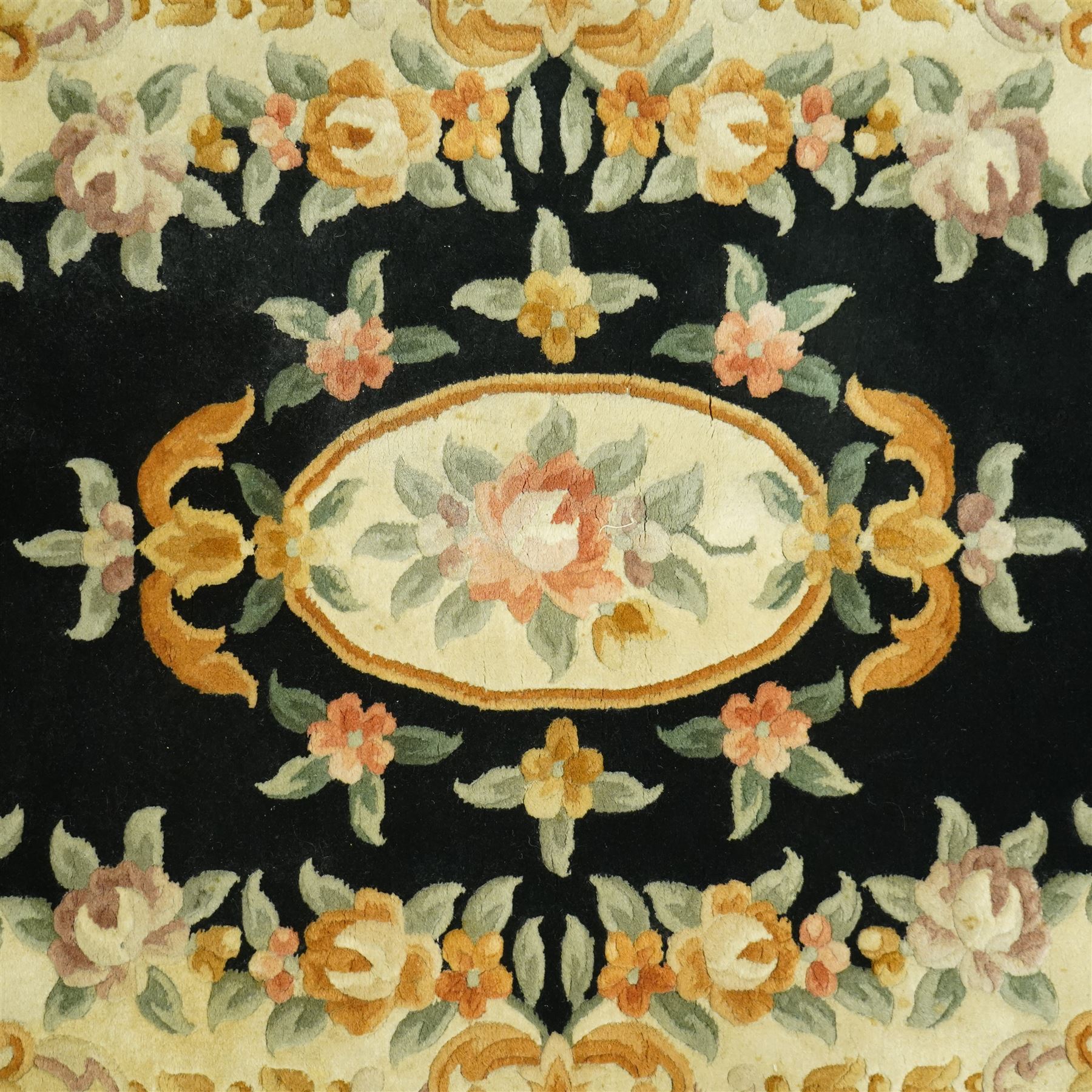 Chinese Aubusson design wool rug, black field with a central oval floral medallion framed by a wide border of scrolling flowers and foliage in soft pastel tones, with ivory spandrels and cotton fringe ends 