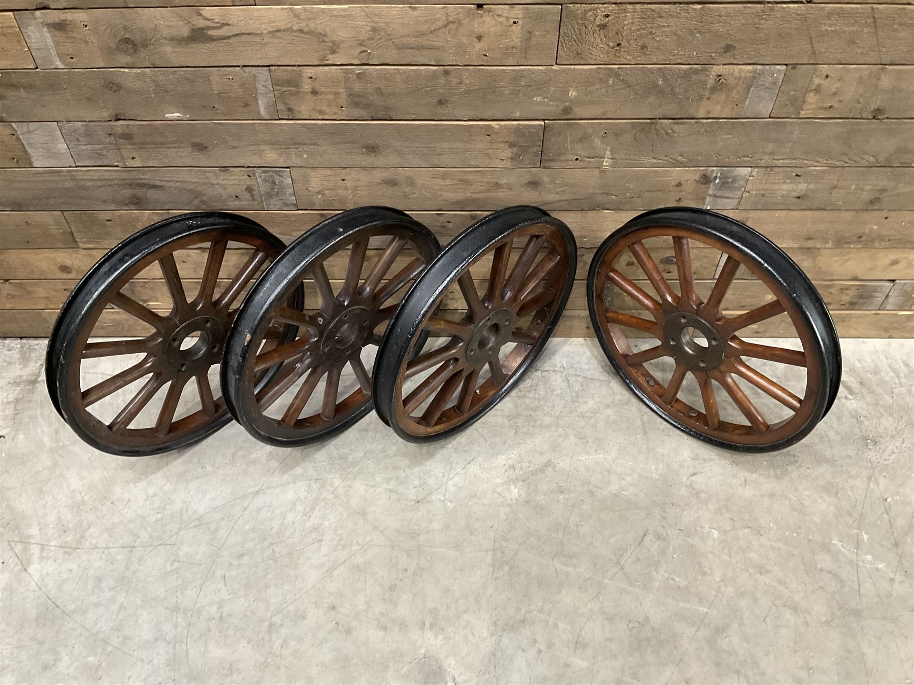 Set of four wheels from an early 20th century cart, wood with metal outer