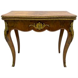 20th century French walnut and Kingwood card table, shaped fold-over top with figured quarter-matched veneers and floral egg and dart moulded edge in gilt metal, shaped aprons decorated with shell motifs with extending foliage, pull-out action base revealing storage well, on cabriole supports with ornate gilt metal mounts 