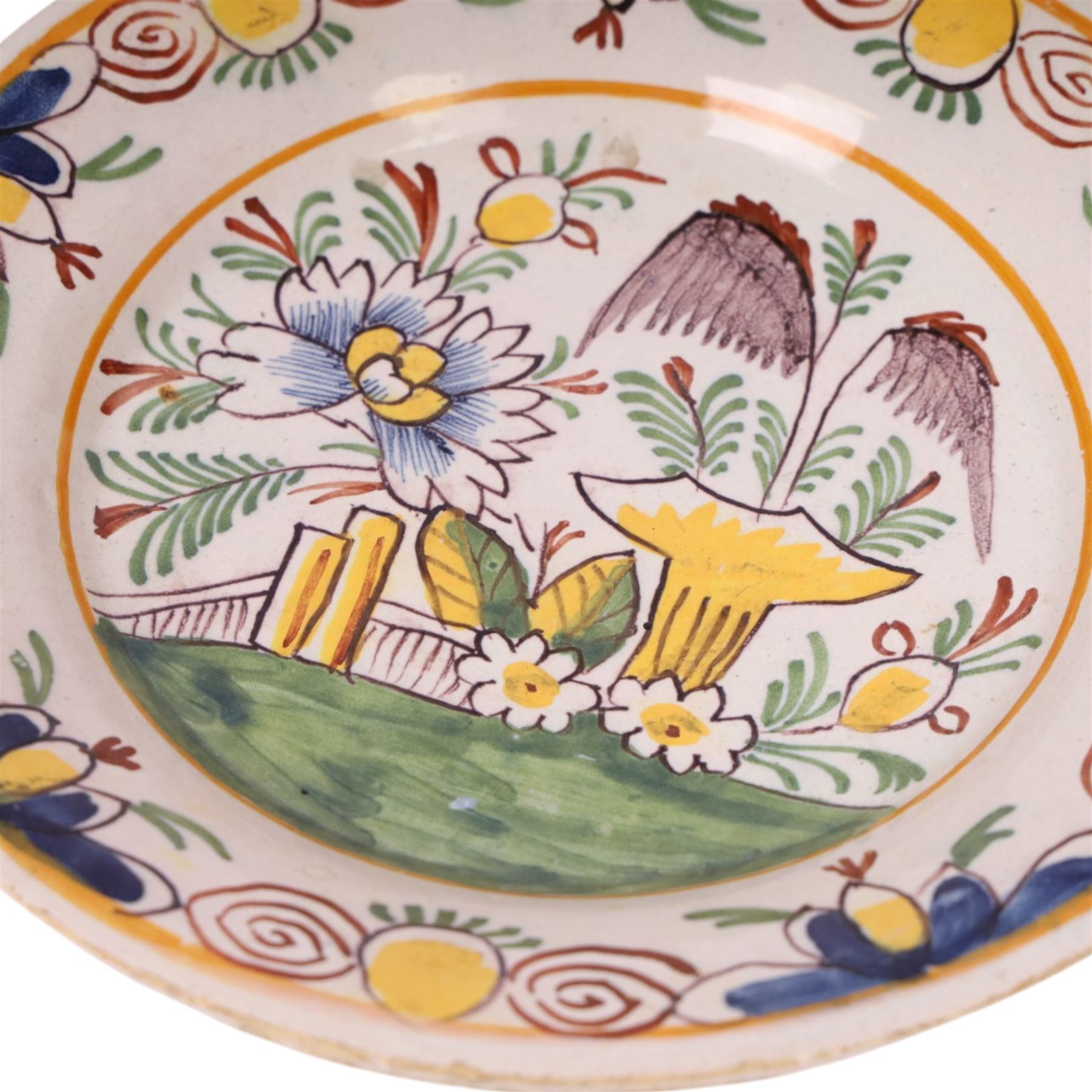18th century Delft polychrome charger, decorated with a central landscape within a stylised floral boarder, D24cm 