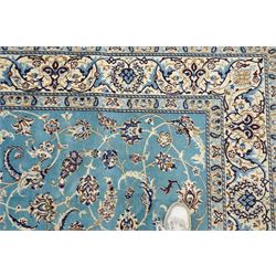 Central Persian Nain hand-knotted carpet, soft sky blue ground with central cusped medallion of radiating palmette form, issuing scrolling vine work, arabesques, and delicate floral sprays, spandrels of conforming design, main border of ivory ground decorated with scrolling vine work palmettes and stylized floral motifs, flanked by narrow guard stripes, with cotton fringe ends 