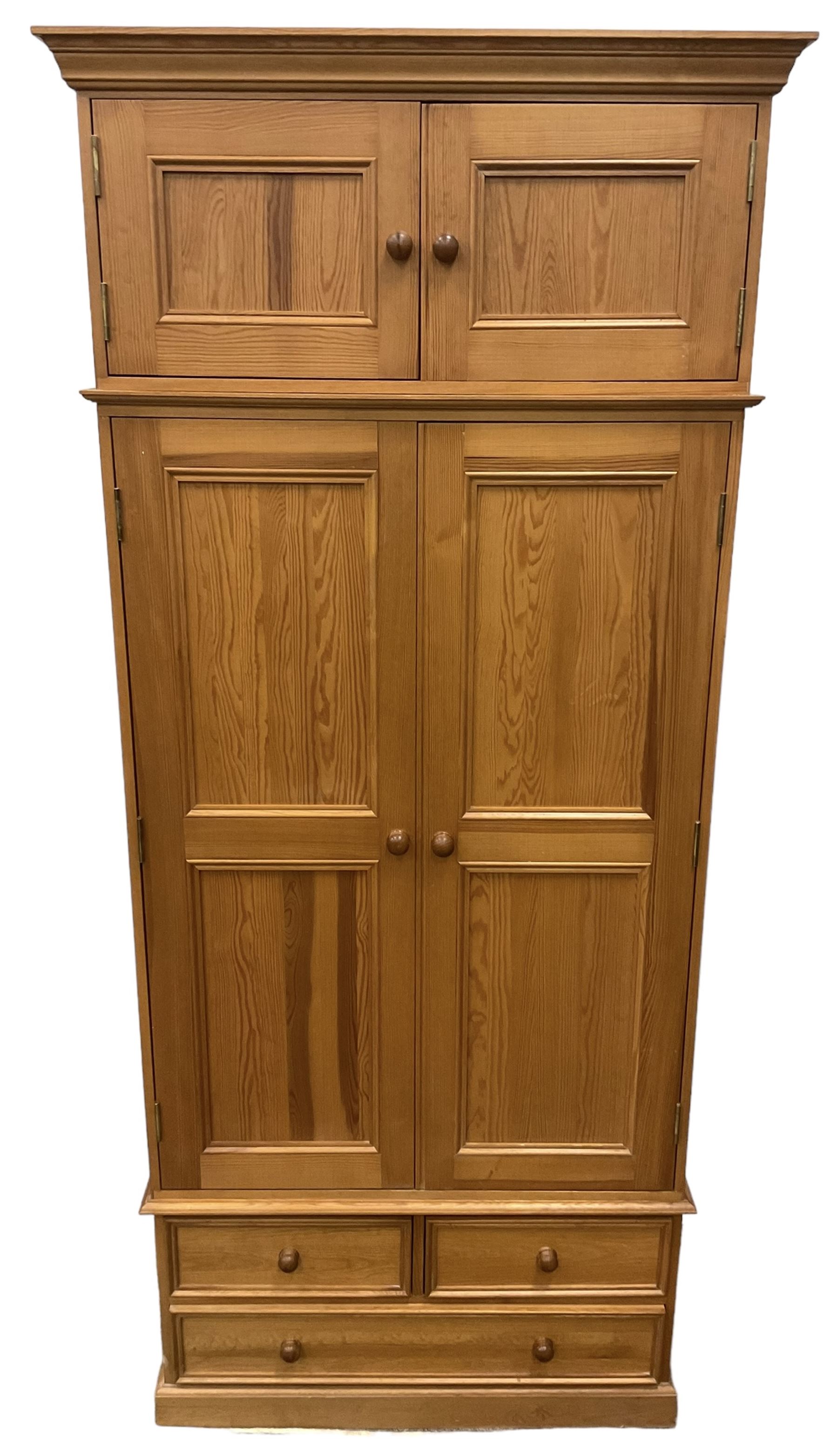 Solid pine double wardrobe, fitted with top box, enclosed by panelled doors, two short and one long drawer, on plinth base 