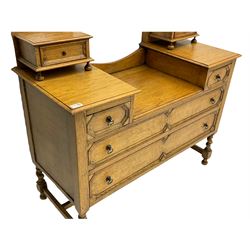 Early 20th century oak dressing chest, oval bevelled swing mirror back, drop centre and fitted with drawers, the drawer fronts decorated with mouldings, spiral turned supports