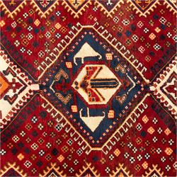 South West Persian Cori hand-knotted rug, red field with three central stepped lozenge medallions enclosing stylized geometric motifs surrounded by scattered rosette devices and angular ornaments within multiple geometric borders, with fringe ends  