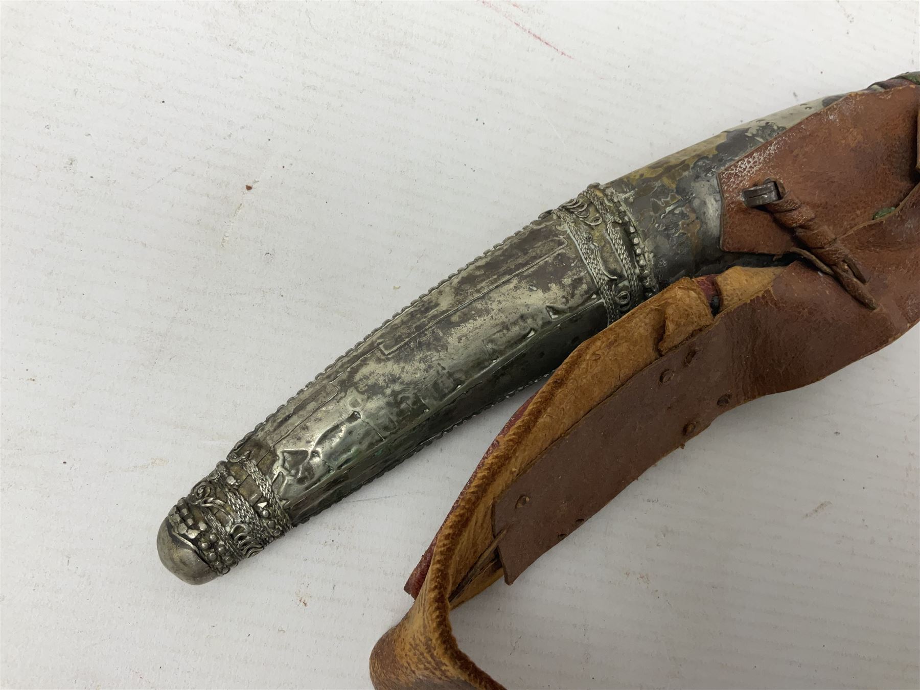 Saudi Arabian khanjar dagger with 29.5cm curving double edged  steel blade; white metal and copper mounted horn grip; in white metal mounted brass and leather scabbard incorporating embroidered leather wearing strap