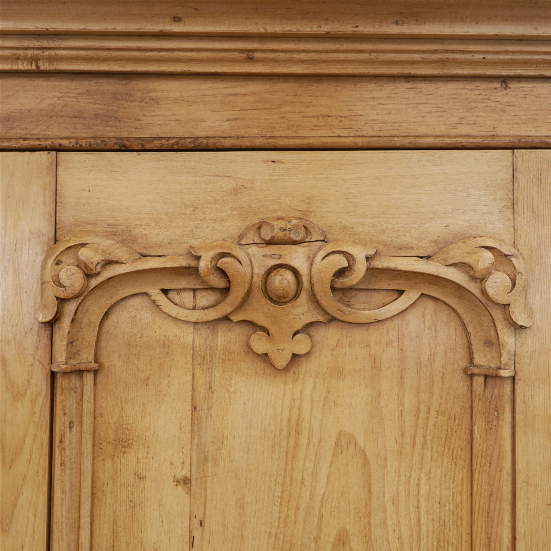 Late 19th century pine wardrobe, with stepped cornice over triple panelled doors, applied foliate carvings to outer panels, raised over a separate pine plinth drawer with moulded facia and twin glass pulls

