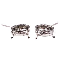 Pair of Edwardian silver open salts, of cauldron form, repousse embossed with flower heads and upon three paw feet, hallmarked London 1904, maker's mark worn and indistinct, together with a pair of silver salt spoons, hallmarked Broadway & Co, London 1906