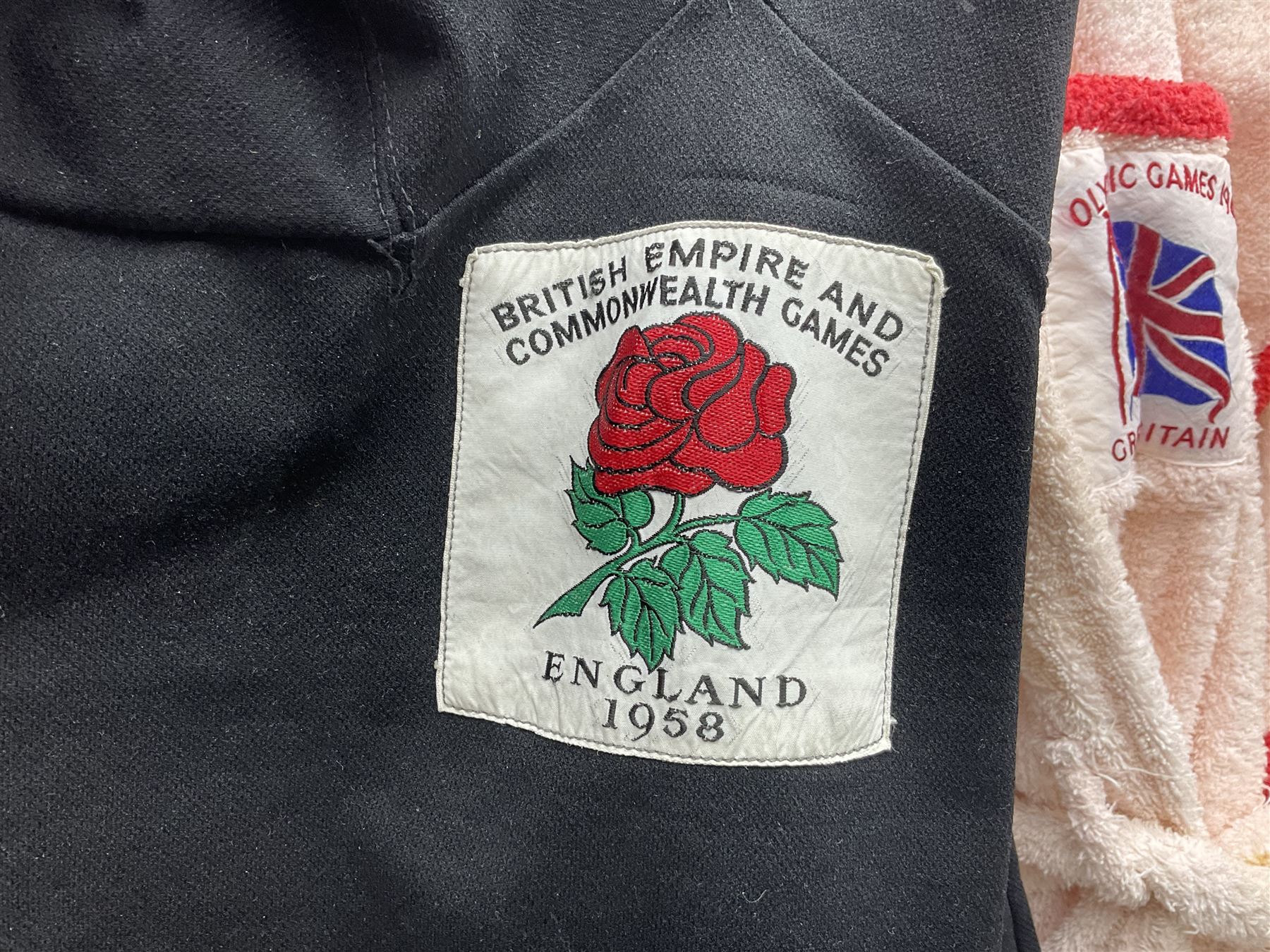 On the direct instructions of Anita Porter nee Lonsbrough Great British Olympic and Commonwealth Games gold medal winning swimmer - collection of early and international memorabilia comprising original Huddersfield Bath Club track suit top bearing eight stitched on cloth badges including British Empire & Commonwealth Games 1958 England Team, YSASA, North Eastern Counties ASA, ESSA Division 3,  English Schools Swimming Association winner etc
The swimming costume Anita wore at the 1958 Commonwealth Games in Cardiff, her first major championships, where she won two gold medals. The grey elastic on the sides, in those days, she would use to make it tighter and more streamlined.
Blue track suit from the 1960 Olympics which she wore on the podium receiving the gold medal.
1960 pool side towelling robe used at the Rome Olympics (interesting to note her name is spelt wrong on the embroidered label).
1962 Commonwealth Games pool side towelling robe used in Perth Australia when winning three Gold medals. 
It was also this year she became BBC Sports Personality of the year, the first female to do so.
Her 'lucky' pool side towel which she took with her to every event she competed in and which can be seen round her neck in many official celebratory photographs. Copies of some of these photographs are included for identification.
In addition there are two souvenir programmes of an evening event to honour Anita at The Theatre Royal Huddersfield and she has kindly signed the front cover on one of these.