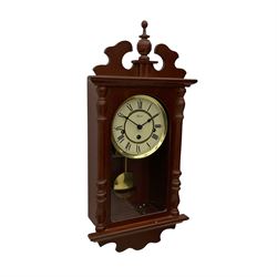 A contemporary 21st century wall clock in a mahogany finished case with a fully glazed door, two-part dial with Roman numerals and steel spade hands, Hermle spring driven eight-day movement with chime/silent feature, visible brass faced pendulum bob.



