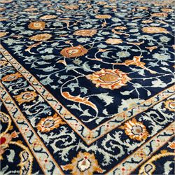 Persian Kashan carpet, navy field with an all-over design of scrolling vines, palmettes and rosettes in gold and pale blue, enclosed by multiple floral borders with stylised palmette motifs, originating from Central Iran