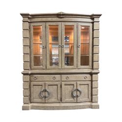 Brunswick - washed oak finish illuminated display cabinet, upper section with four glass-panelled doors enclosing glass shelving, base fitted with two drawers over four paneled cupboard doors, each fitted with distinctive round metal handles, raised on plinth base